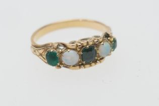 Emerald and opal five stone ring, having three small cushion cut emeralds dispersed with two