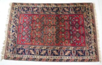 Anatolian red ground woollen carpet, dispersed with dark blue hooked lozenges, within a deep blue