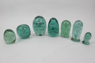 Seven Victorian green glass dumps, each encasing a floral design and generally ovoid in shape, the