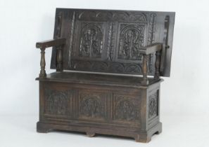 Late Victorian or Edwardian carved oak monk's bench, the lifting top with a lunette carved frieze