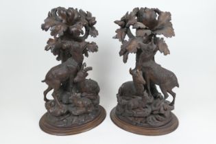 Pair of Black Forest carved limewood table centres, each carved as deer at the base of trees, height