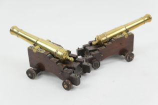 Pair of ornamental brass cannons, 17cm, raised on wooden carriages, total length 23cm (Please note