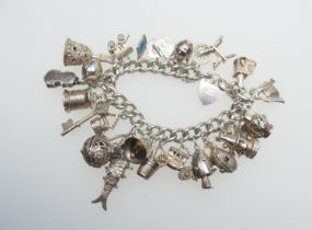 Silver curb link charm bracelet, with padlock clasp, supporting 25 silver charms, gross weight