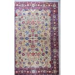An Antique Tabriz Carpet, woven in colours of ivory, navy blue and wine, the field filled with