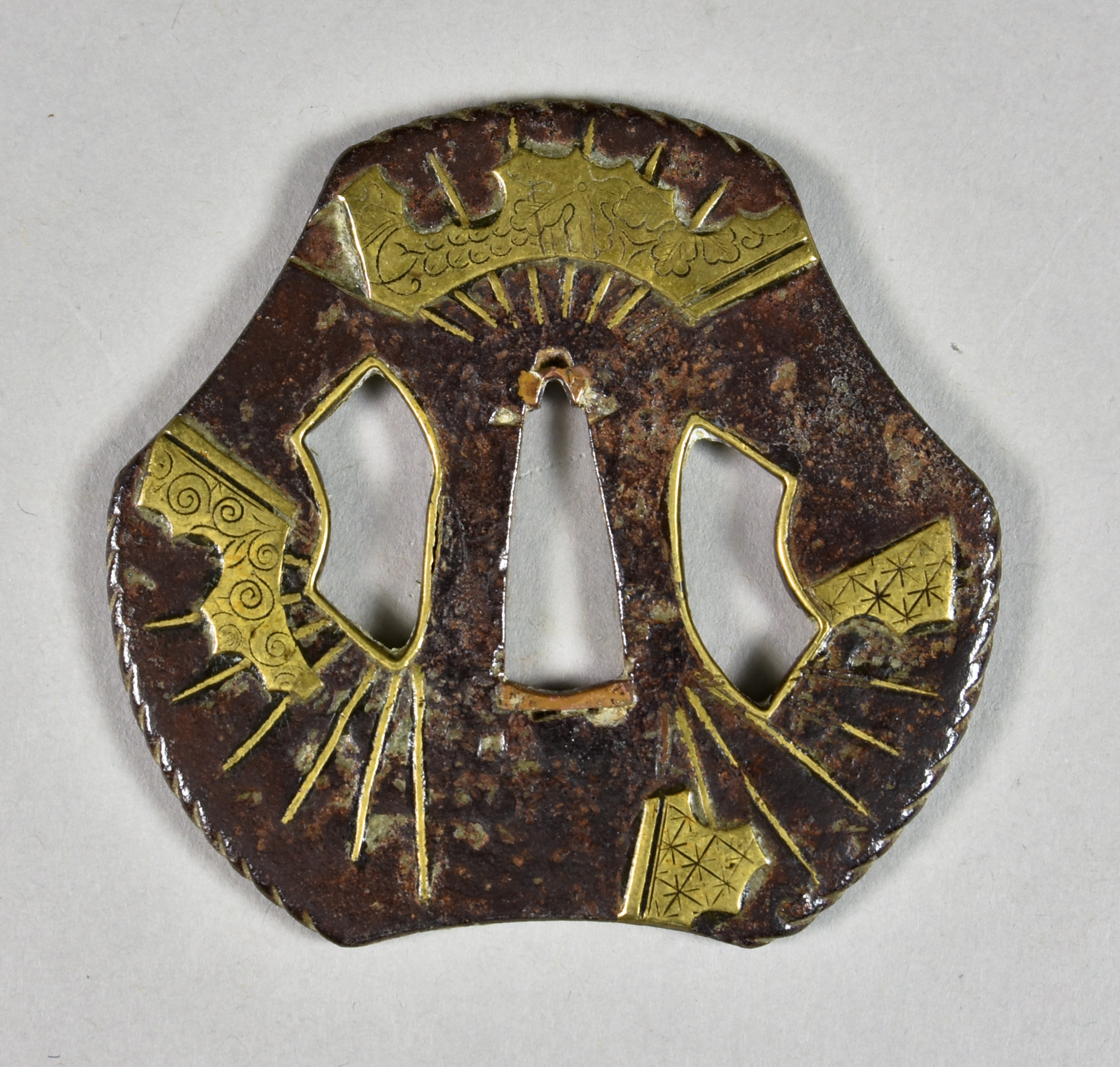 A Japanese Tsuba, iron Heianjo School depicting broken fans inlaid with brass, Edo period (1615-