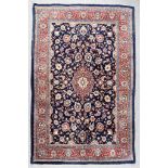 A 20th Century Kashan Rug, woven in colours of navy blue, ivory and wine, with a bold central