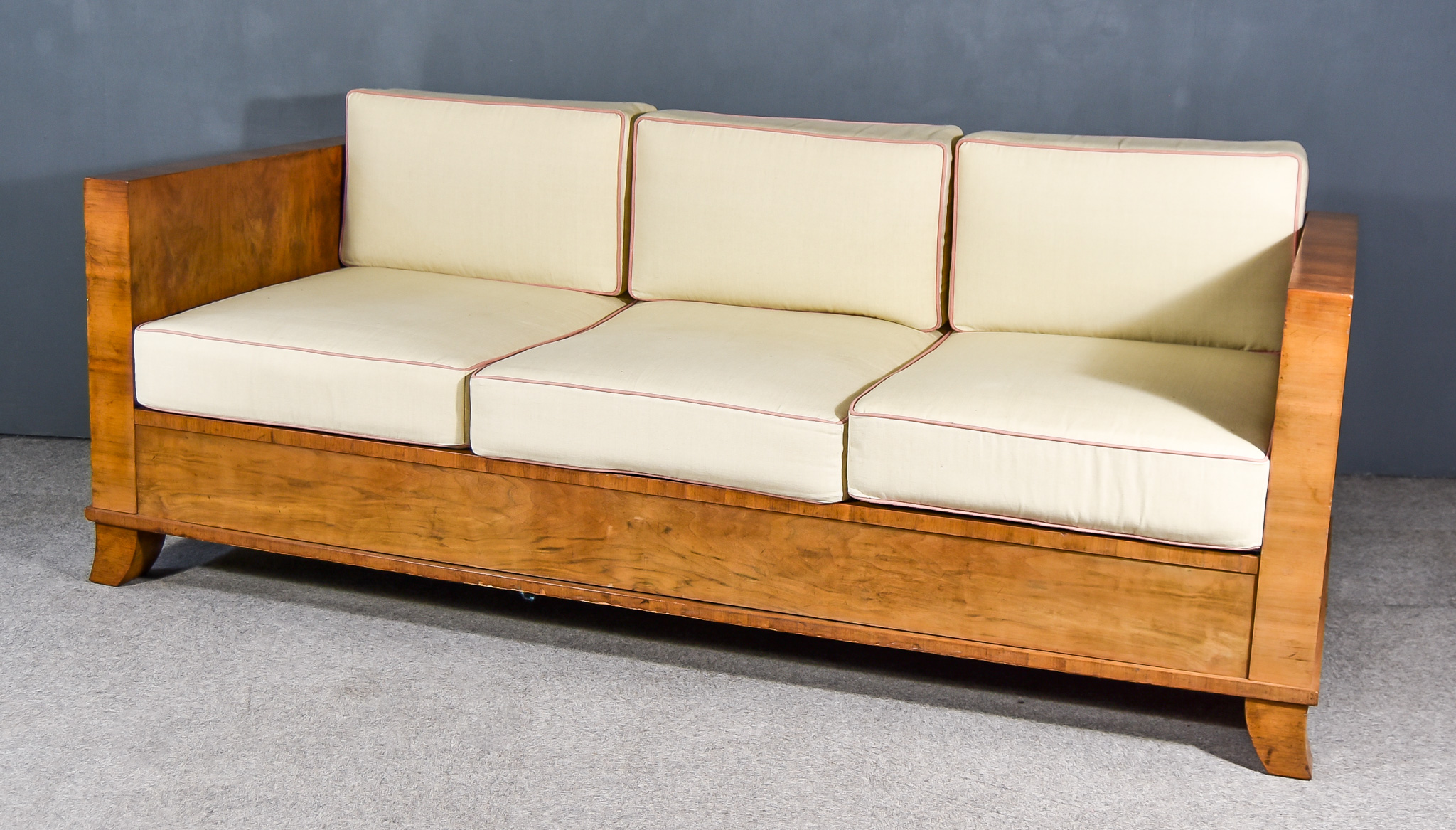 A 1930s Continental Walnut Day Bed, of Art Deco design, on splayed feet with cream upholstered loose