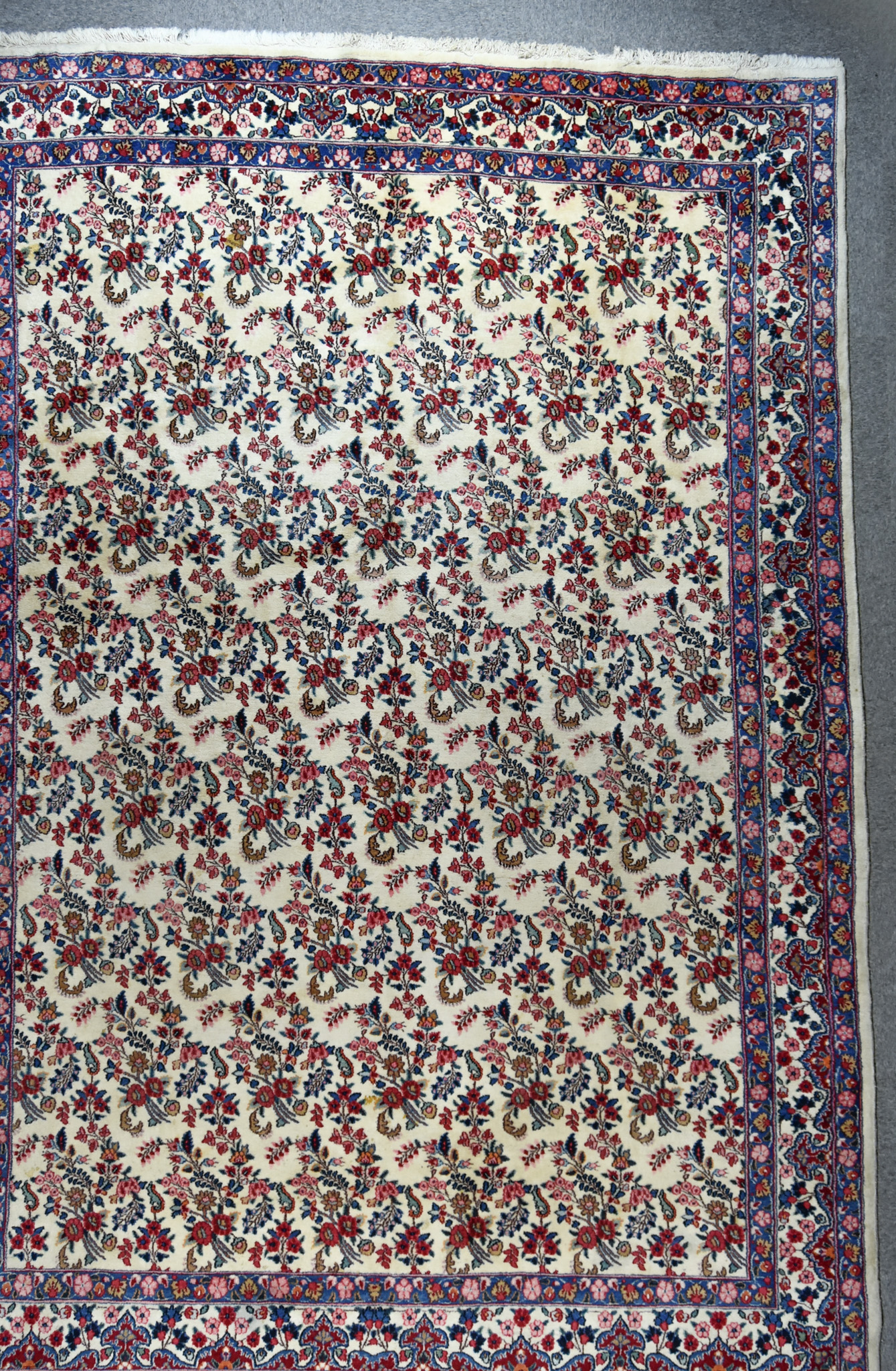 An Early 20th Century Qum Carpet, woven in colours of ivory, navy blue and wine, the field filled