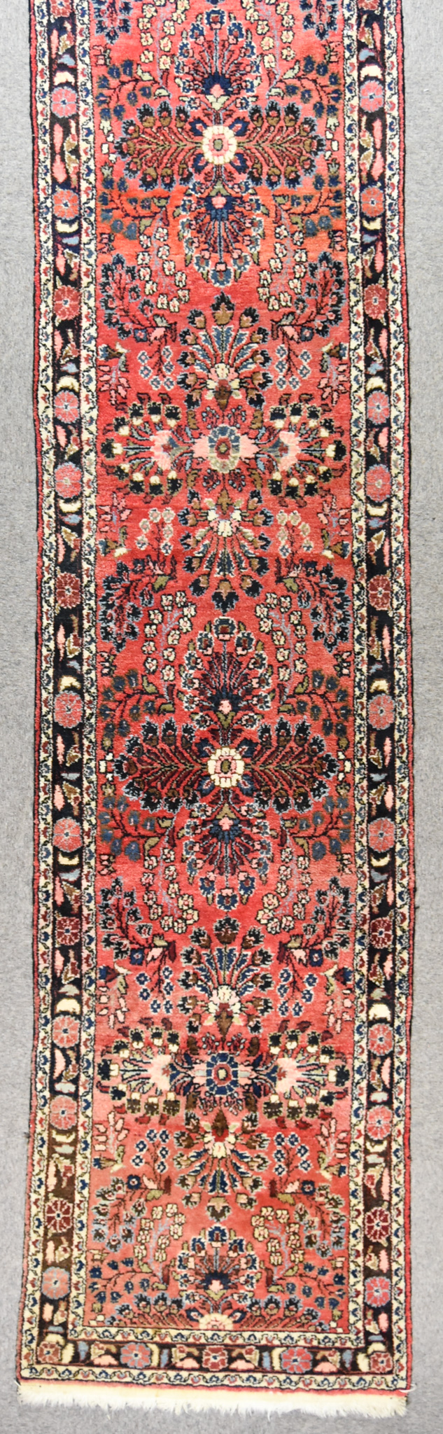 A 20th Century Darjazian Runner, woven in colours of rose, ivory and navy blue, with nine stylised