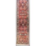 A 20th Century Darjazian Runner, woven in colours of rose, ivory and navy blue, with nine stylised