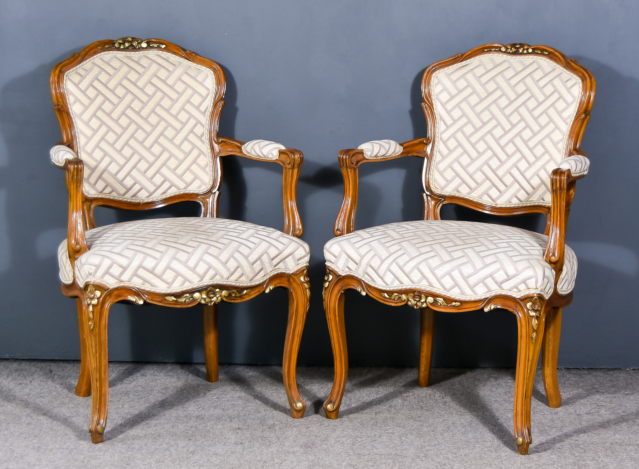 A Pair of French Walnut and Parcel Gilt Fauteuils of "Louis XV" Design, with shaped and moulded