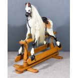 A 20th Century Dappled Grey Rocking Horse, on turned oak base with trestle feet, 56ins x 46ins high