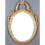 A Gilt Framed Oval Wall Mirror, with leaf scroll and ribbon cresting, 41ins x 29ins overall