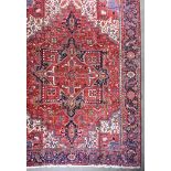 An Antique Heriz Carpet, woven in colours of ivory,navy blue and wine, with a bold central cross