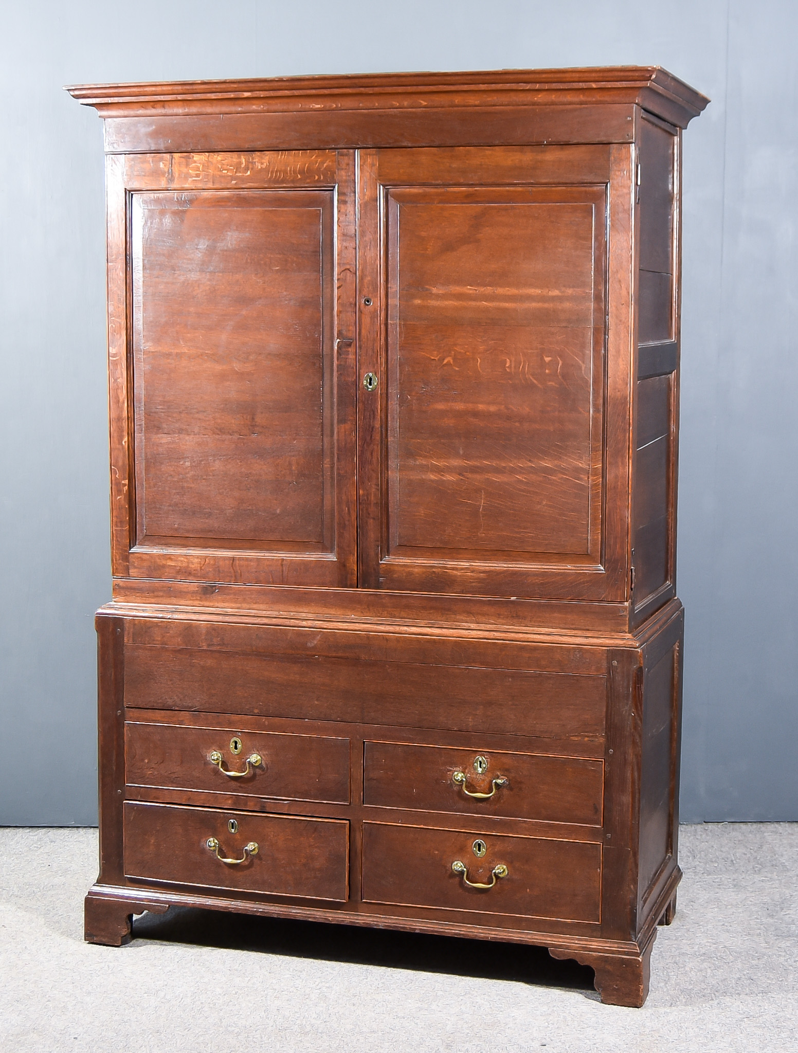 An 18th Century Panelled Oak Wardrobe, with moulded cornice and fitted hanging rail enclosed by a