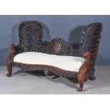 A 19th Century Burmese Hardwood Love Seat, the shaped back fretted and carved with leaf,