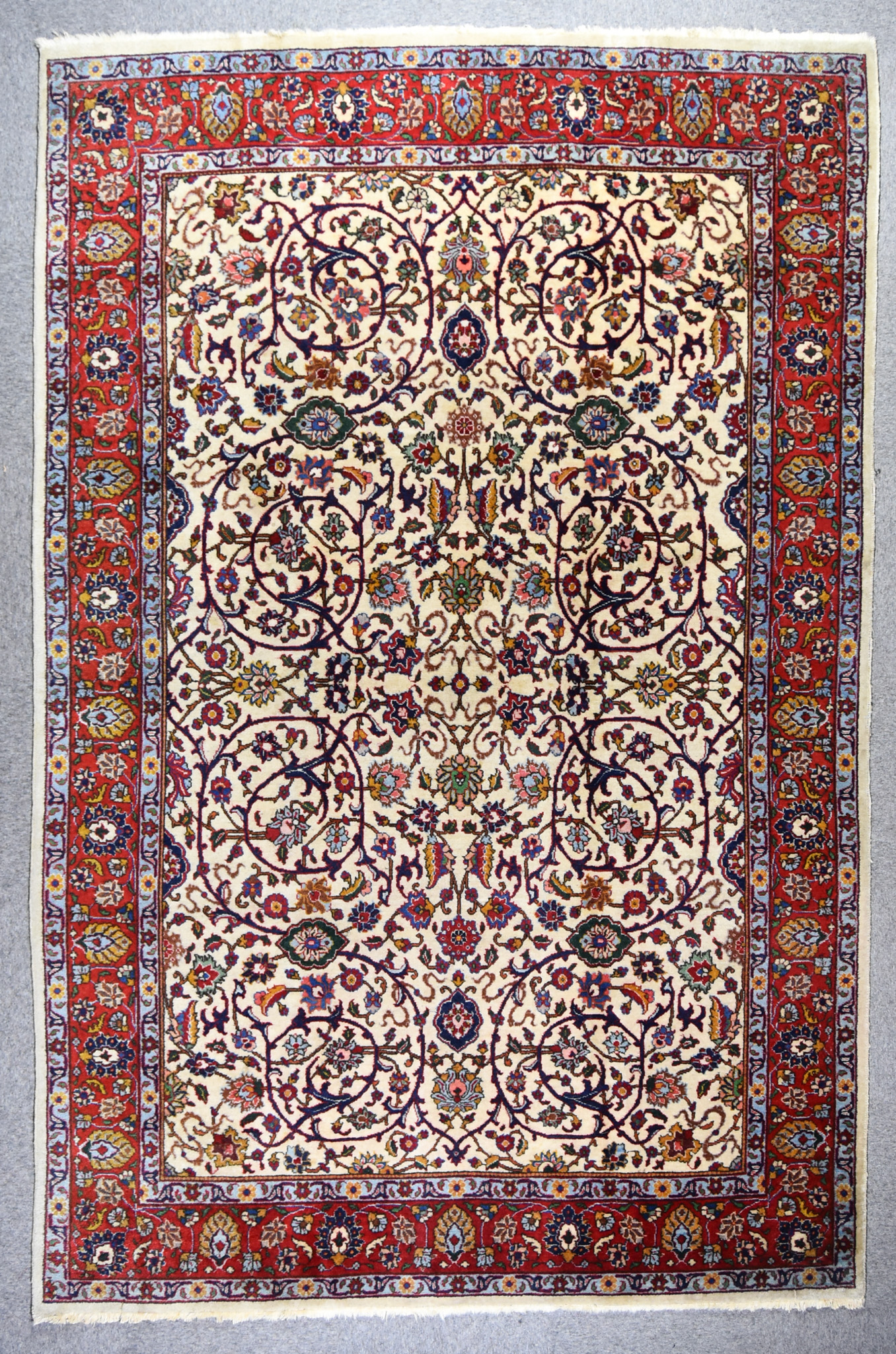 An Antique Tabriz Carpet, woven in colours of ivory, navy blue, green and wine, the field filled