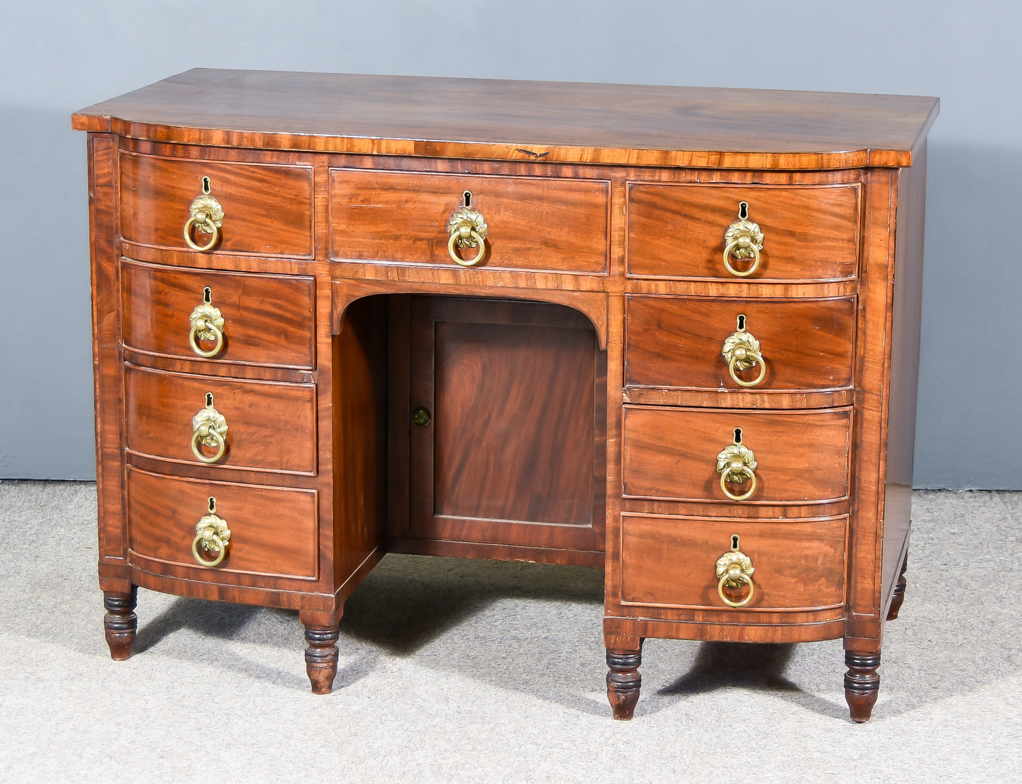 A George IV Bow Fronted Figured Mahogany Dressing Table, with square edge to top, fitted nine