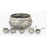 A Burmese Silvery Metal Circular Bowl and Five Condiments, the bowl embossed with elephants in