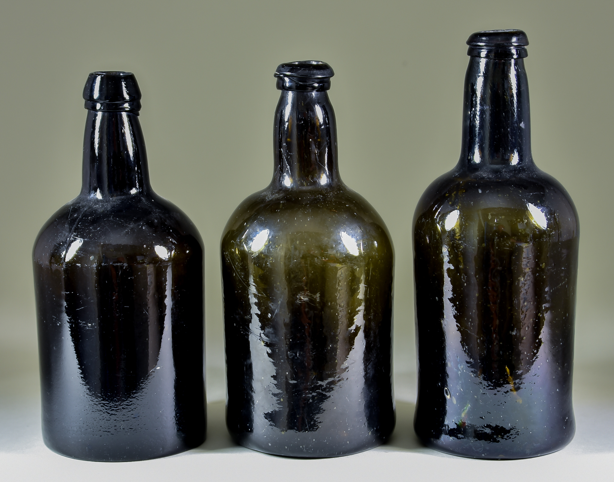 A Wine Bottle of Cylindrical Form of Olive Green Tint, Late 18th Century, with moulded string rim,