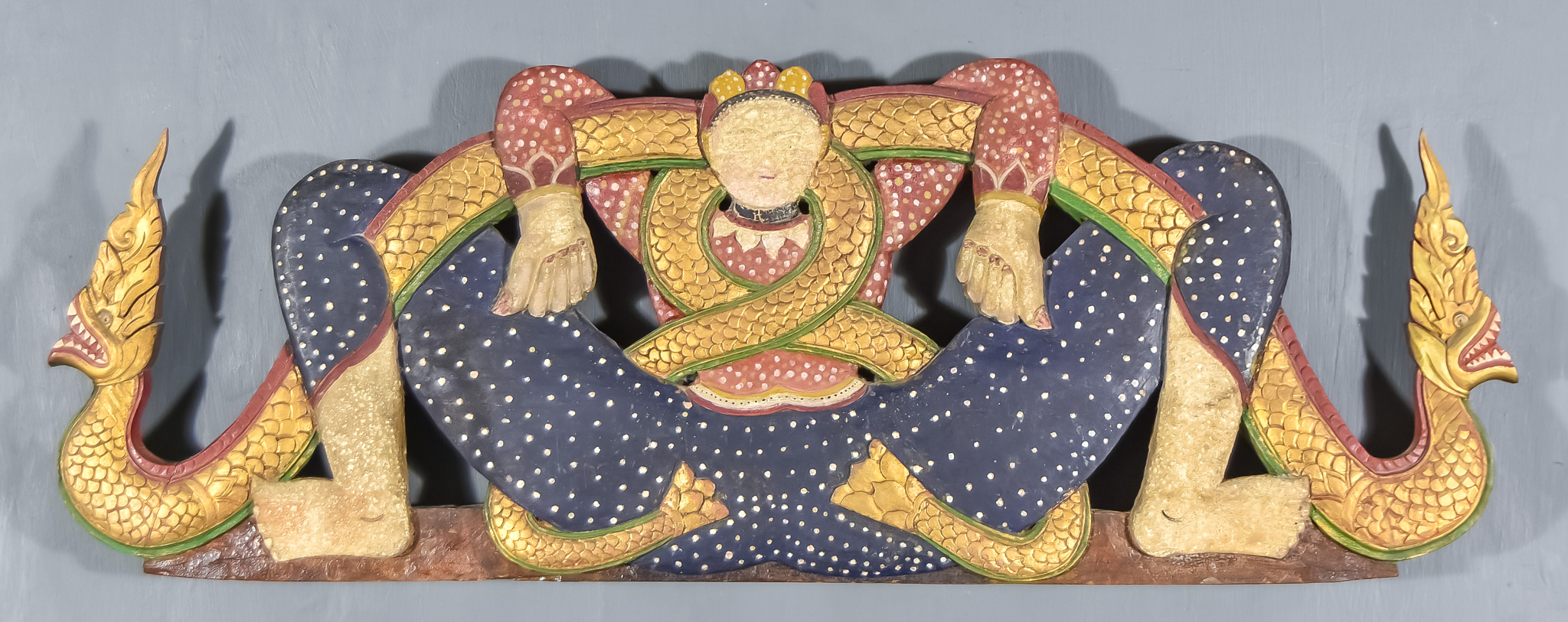 An Eastern Carved Polychrome and Giltwood Wall Plaque, carved as a man with entwined dragon,