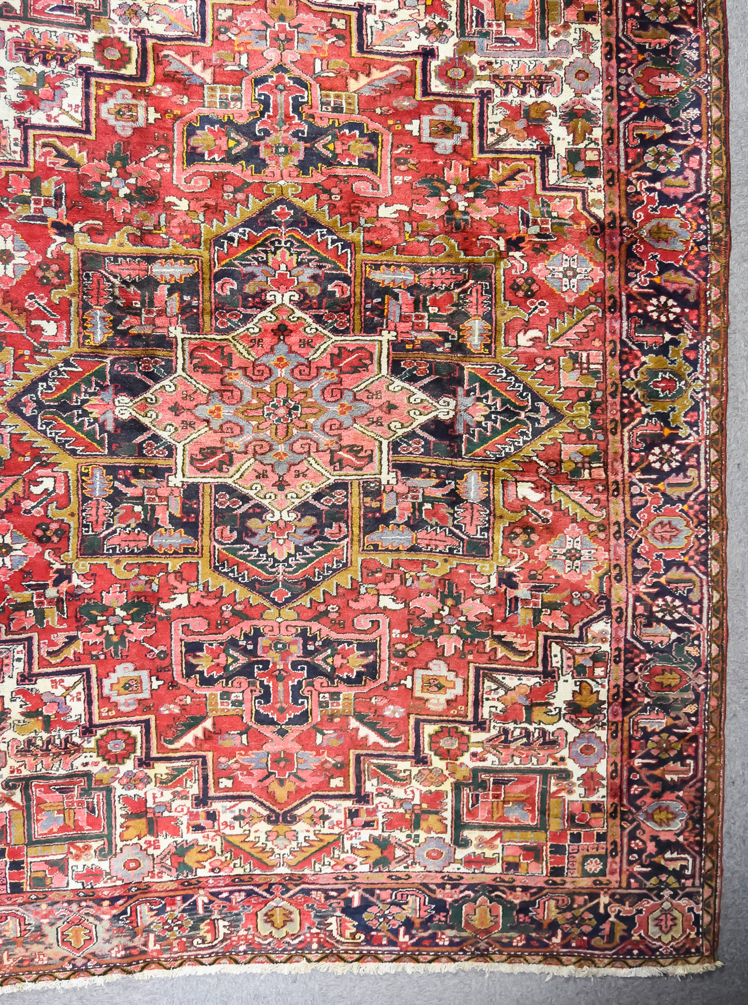 An Antique Heriz Carpet, woven in colours of ivory,navy blue and wine, with a bold central cross