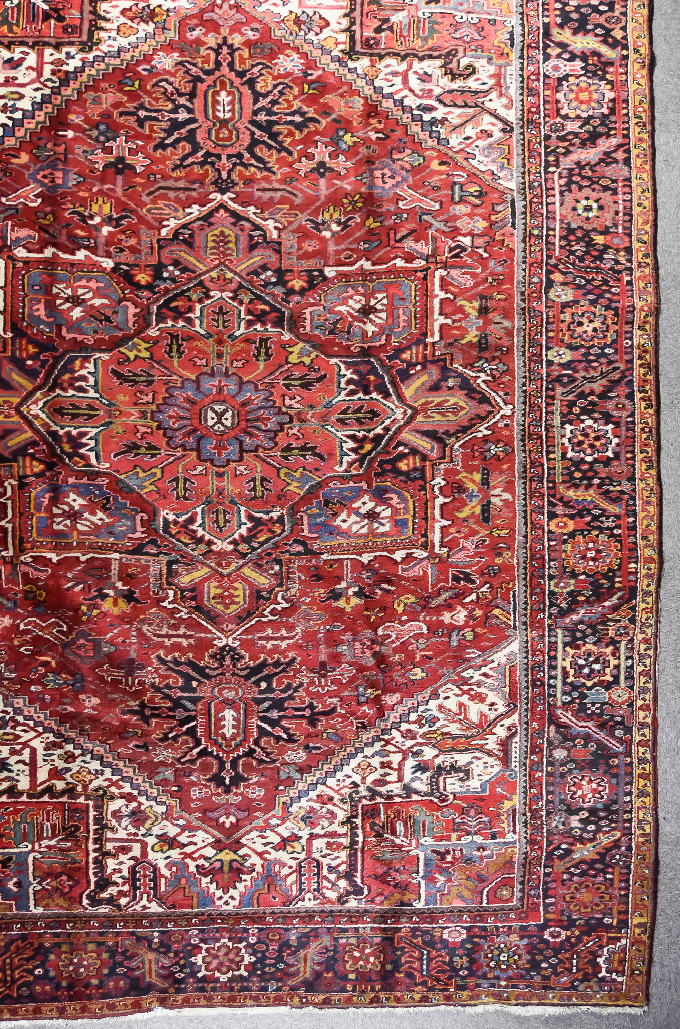 An Antique Heriz Carpet, woven in colours of ivory, navy blue and wine, with a bold central cross
