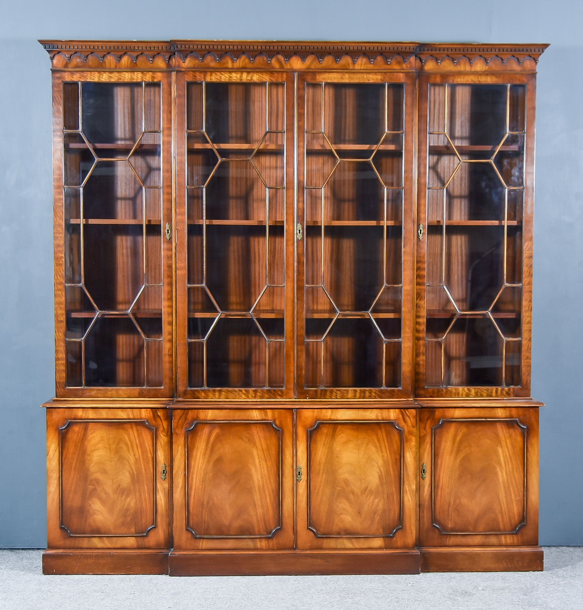 A Mahogany Break Front Bookcase of "Georgian" Design, the upper part with moulded cornice, dentil