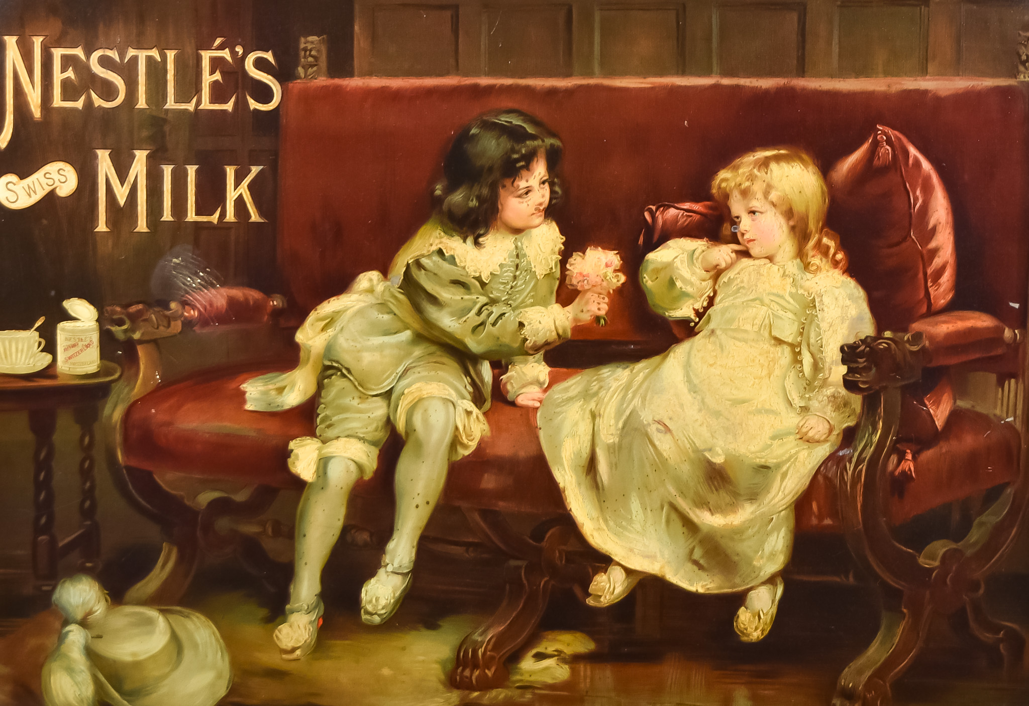 A Nestle's Swiss Milk Framed Advertising Show Card, with two children on a sofa, 19.75ins x 28.