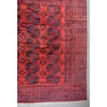 A 20th Century Afghan Carpet, woven in colours of madder and navy blue, the field filled with
