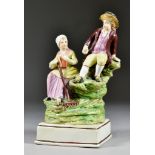 An English Pearlware Pottery Group, Early 19th Century, of seated rustic figures of a man and woman,