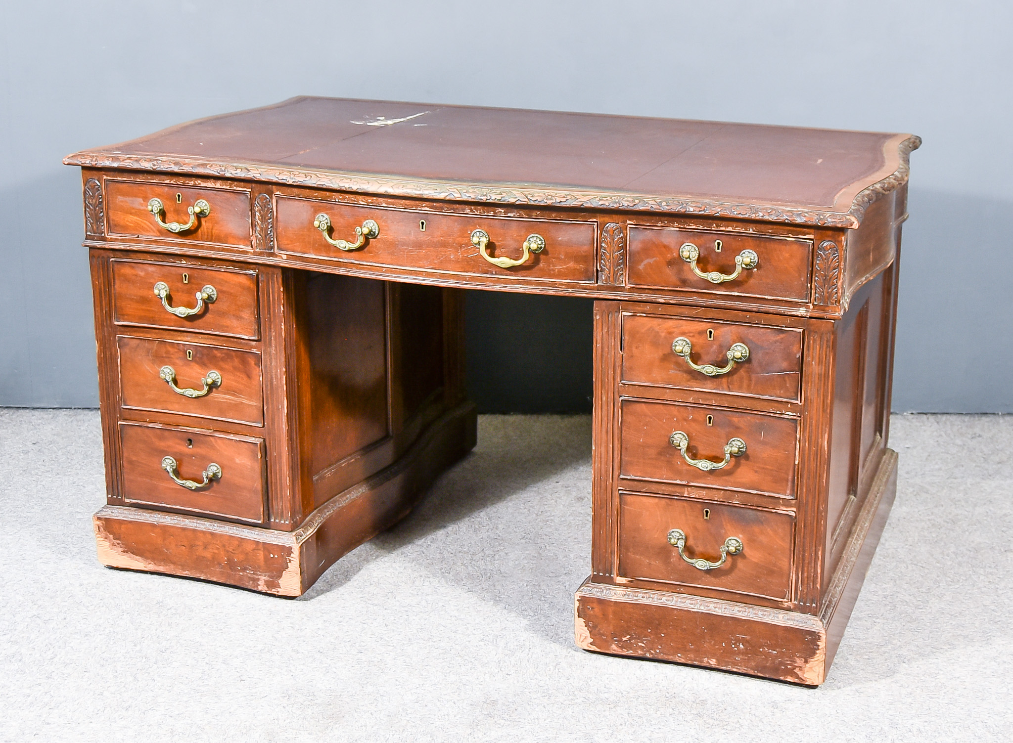 An Early 20th Century Mahogany Kneehole Desk of Serpentine Outline with brown leather cloth inset