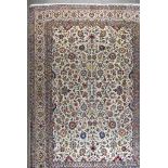 An Antique Kashan Carpet, woven in colours of ivory, navy blue and wine, the field filled with