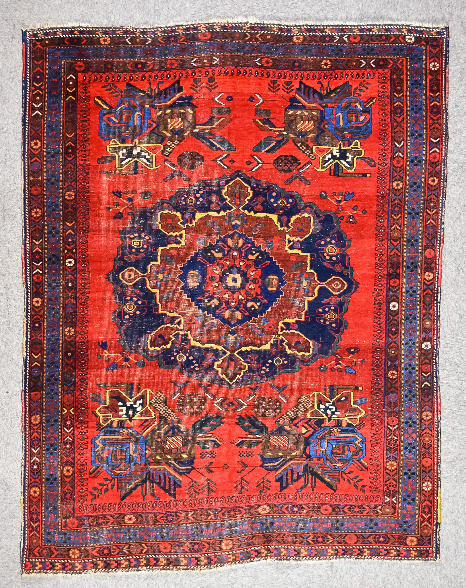 An Antique Afshar Rug, woven in colours of ivory, navy blue and wine, with a bold central floral