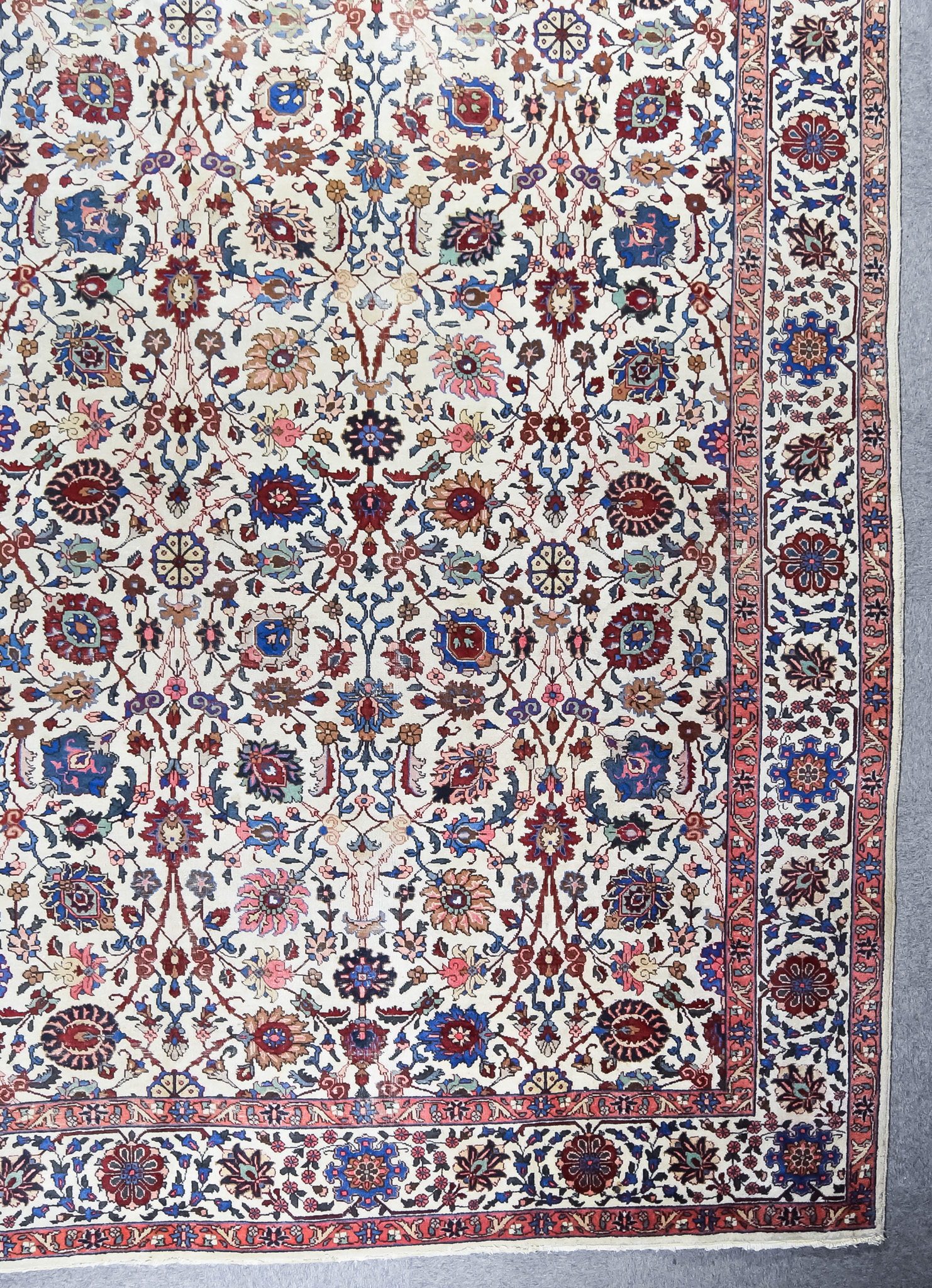 A Fine Antique Tabriz Carpet, woven in colours of ivory, navy blue, wine and fawn, the field