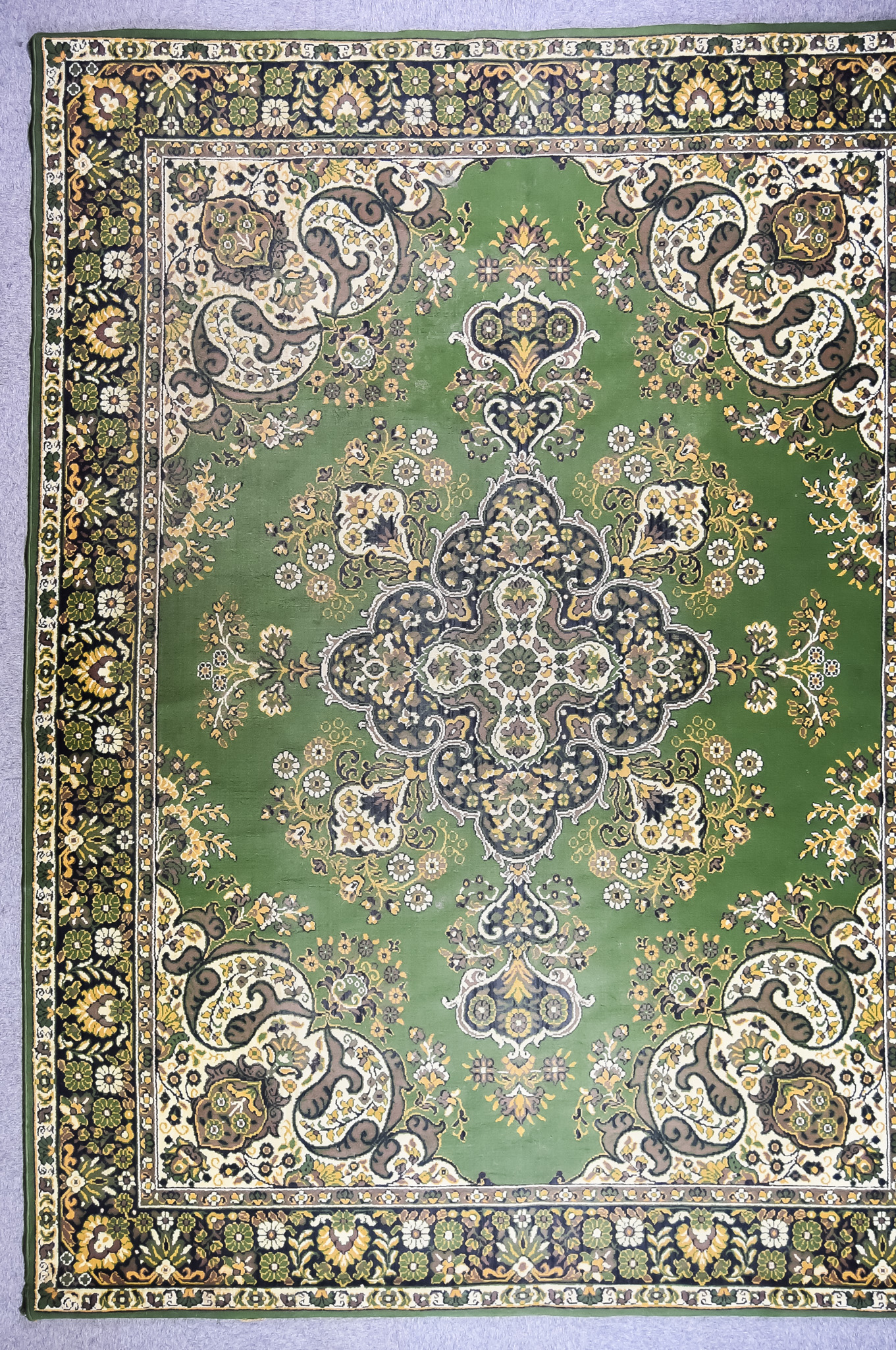 A 20th Century Indian Carpet of Kirman Design, woven in colours of green, ivory and fawn, the bold