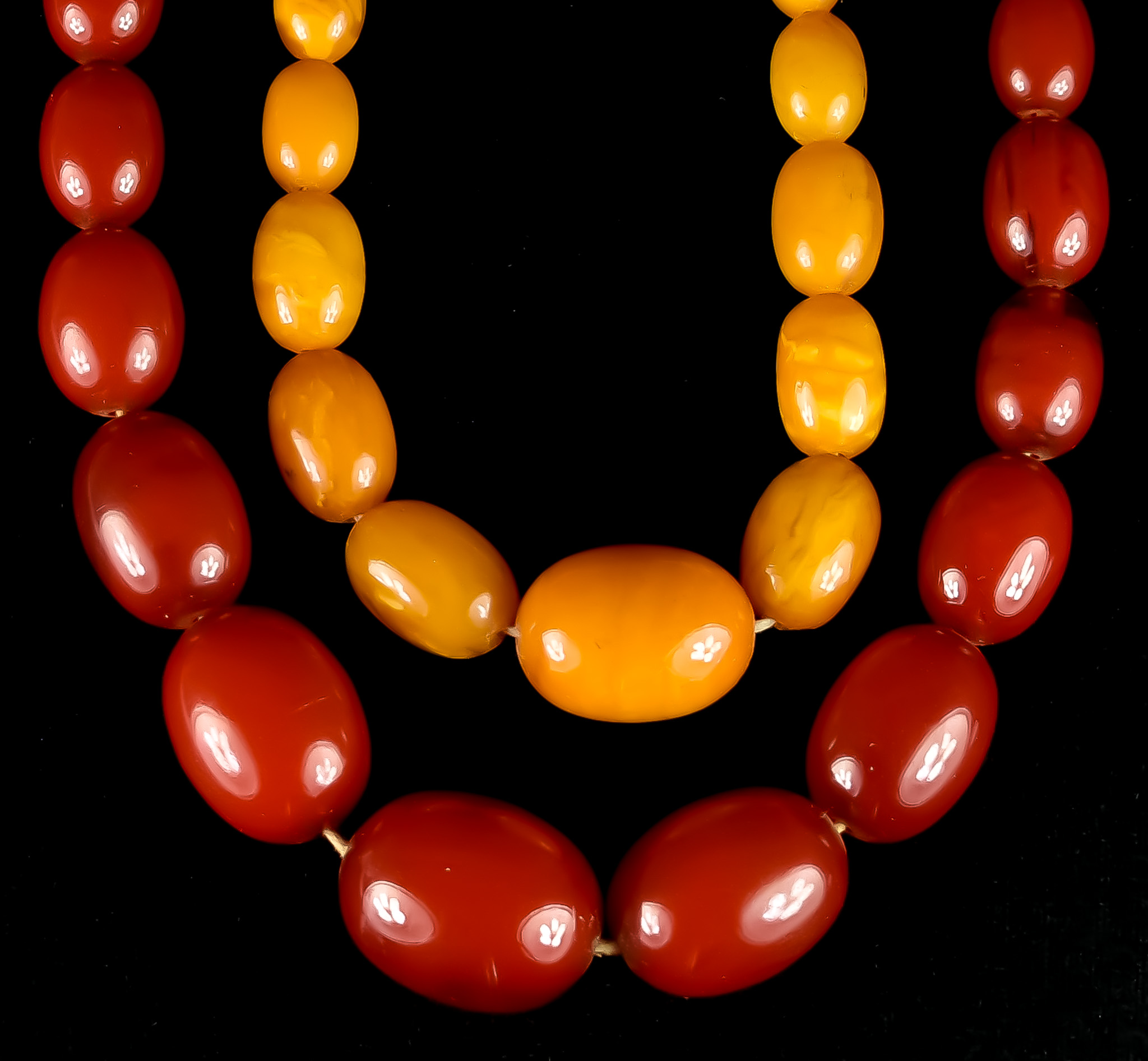 Two Strings of Amber Beads, one string of red amber graduating beads, 11mm to 30mm in diameter,