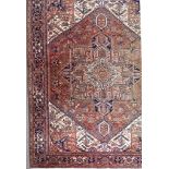 An Antique Heriz Carpet, woven in colours of ivory, navy blue and wine, the bold central stylised