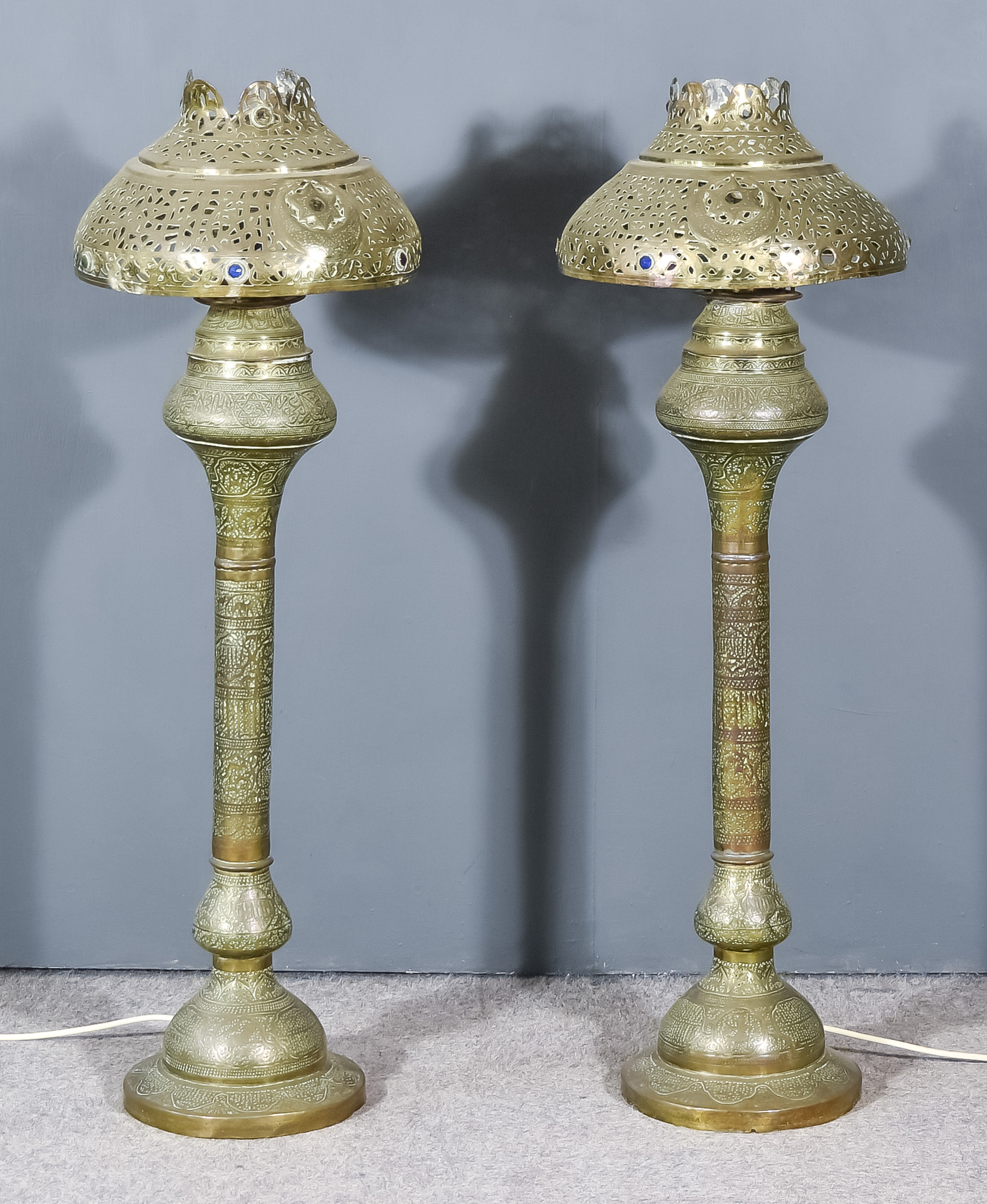 A Pair of Near-Eastern Brass Embossed Table Oil Lamps, now converted to electric, with knopped and