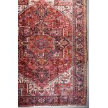 An Antique Heriz Carpet, woven in colours of ivory, navy blue and wine, with a bold central cross