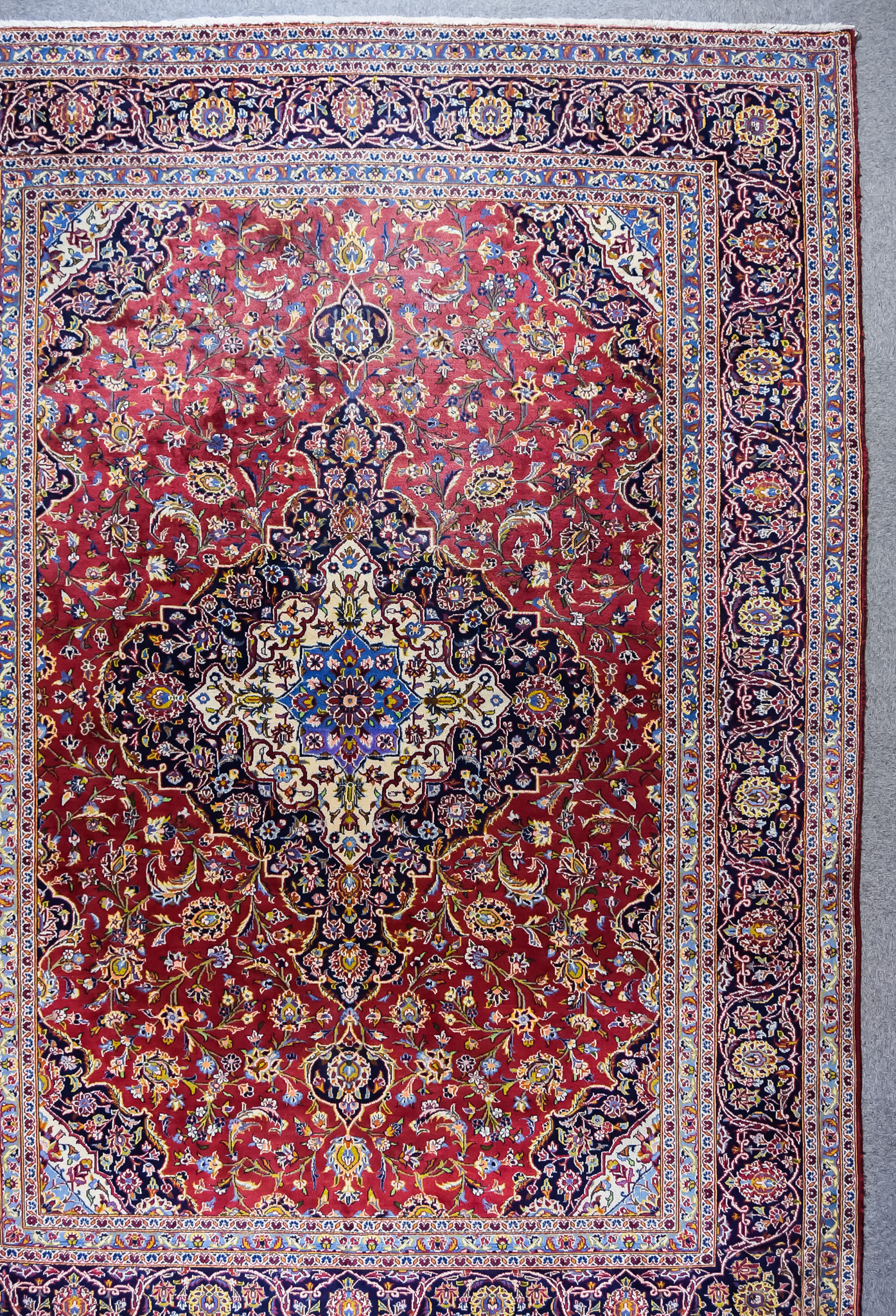An Early 20th Century Tabriz Carpet, woven in colours of ivory, navy blue and wine, bold central