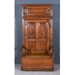 An 18th Century Panelled Pine and Elm "Bacon" Settle, with moulded edge and cupboard, enclosed by