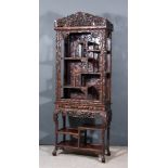 A Chinese Rosewood Display Cabinet, the whole carved with blossom and leaves, the top with fretted