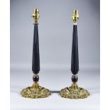 A Pair of Ebonised and Cast Brass Electric Table Lamps, with tapered reeded stems on shaped cast