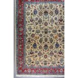 An Antique Tabriz Carpet, woven in colours of ivory, navy blue and wine, the field filled with