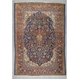 An Early 20th Century Tabriz Rug, woven in colours of ivory, navy blue and wine, the bold central
