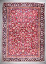 An Antique Kashan Carpet woven in colours of madder, navy blue and fawn, the field filled with