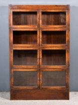 A 1920s Oak Four Tier Sectional Bookcase, each section enclosed by a pair of glazed doors, on plinth