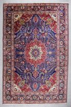 An Early 20th Century Tabriz Carpet woven in colours of green, navy blue, ivory and wine, with a