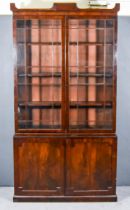 A George IV Figured Mahogany Library Bookcase, the shaped cornice with brass inlay, fitted three